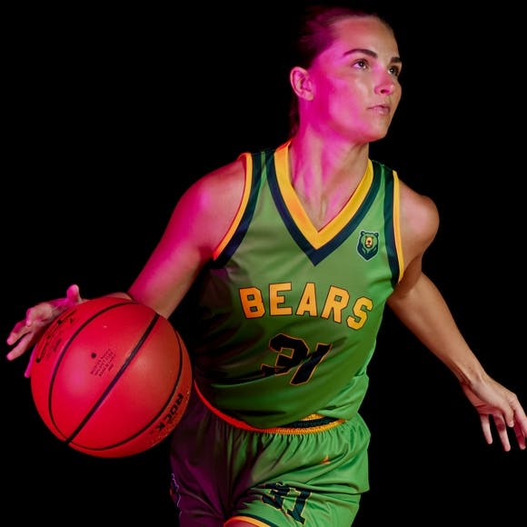 Girl basketball athlete dribbling a basketball and wearing a BSN SPORTS reversible uniform