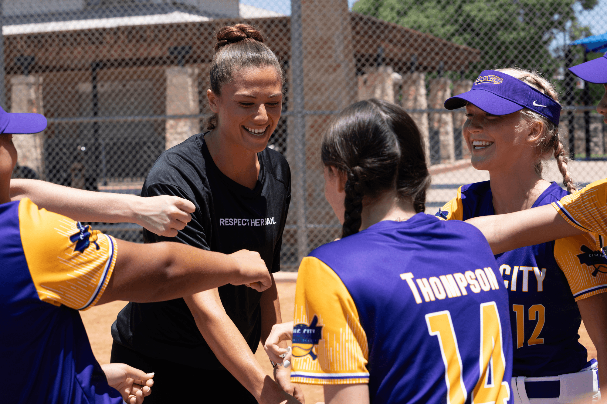 a softball team in a huddle with their coach before a game