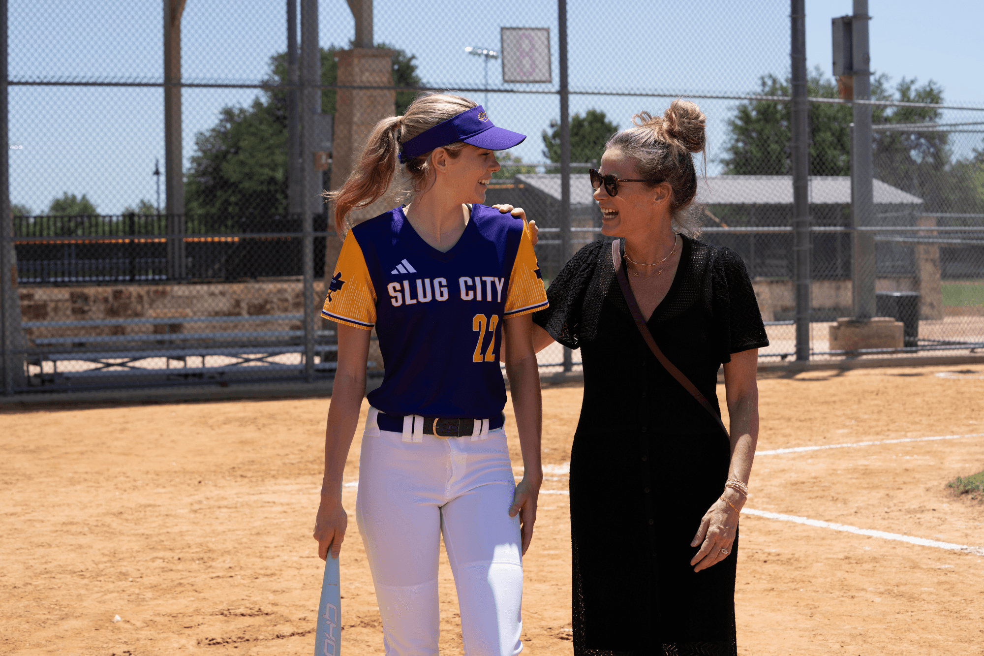 a softball player walking off the field while talking to her mom